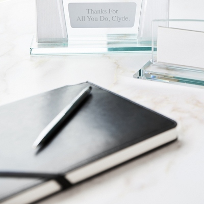 Whether they're fresh out of school or gunning for a promotion, the Cross Century Chrome Ballpoint Pen and Journal Set will have them leaving the best impression anywhere they go. A classic chrome ballpoint pen offers a smooth writing tool for all their daily needs and is paired with a black leatherette journal for jotting notes or perfecting doodles in their down time. Complete the gift by engraving their name, new job role, a significant date or fun message on the plate. -Contents: Includes ballpoint pen and journal with a pen holder on the side -Size: 0.3" W x 5.2" L (Pen)-Material: Brass (Pen), Leatherette, Paper (Journal)-Refill: Cross #8513 Medium Black -Inspiration: A great gift for a coworker, employee or friend. Cross Century Chrom